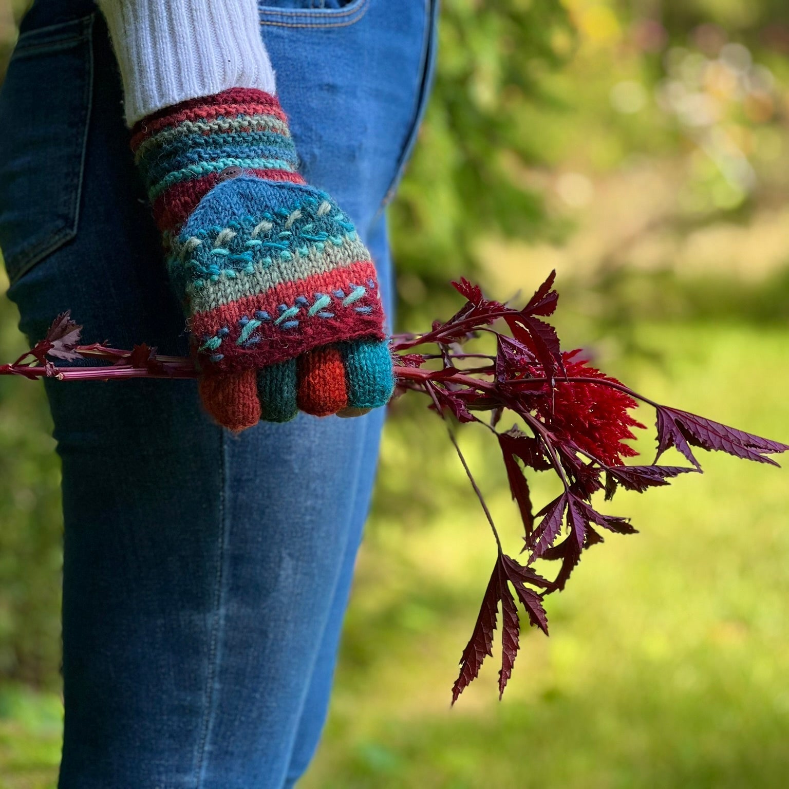 A person wearing multicolored finger mittens with a crochet pattern by Lost Horizons