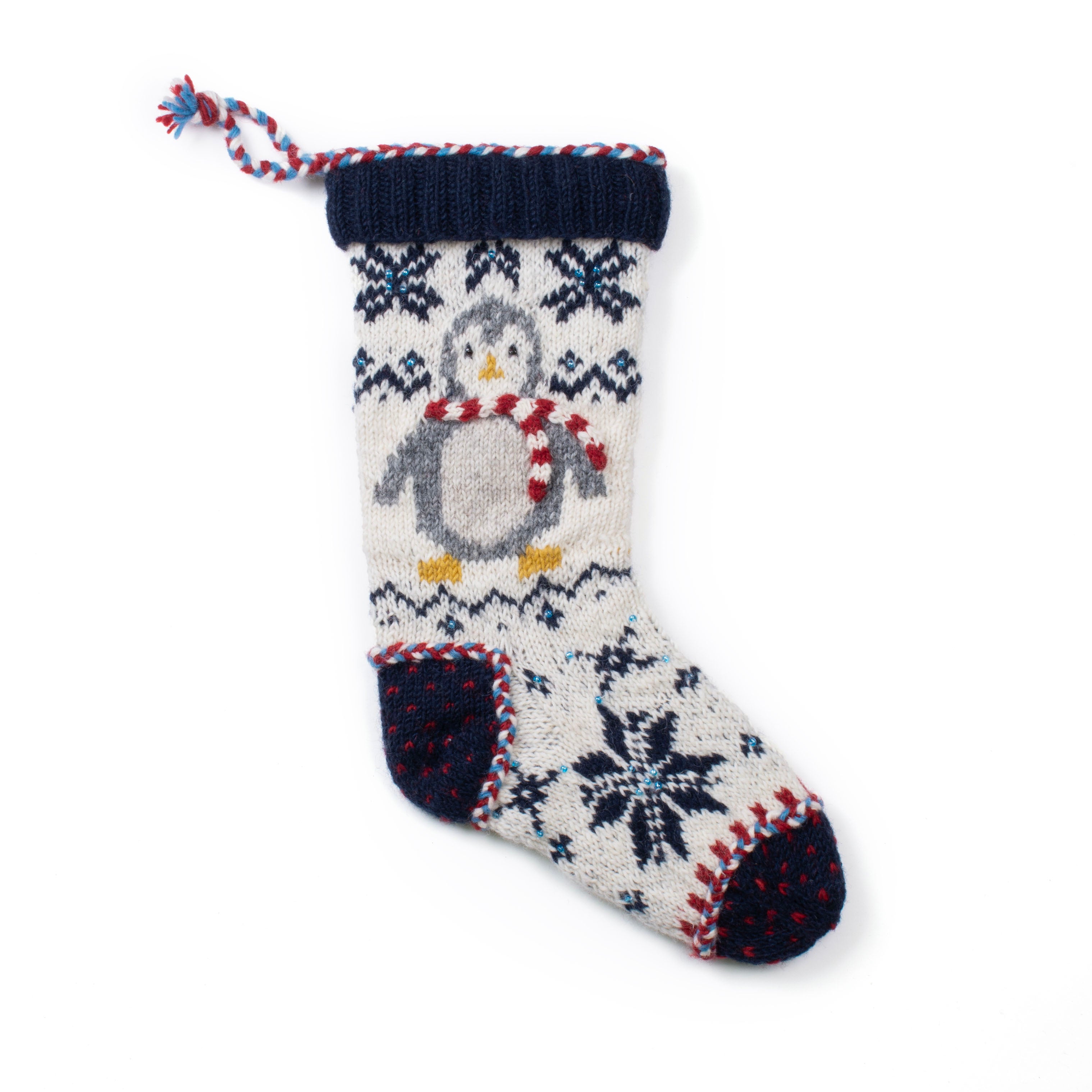 Hand-knit wool Christmas stocking featuring a penguin with a red scarf and snowflake pattern, handmade in Nepal through Fair Trade craft.